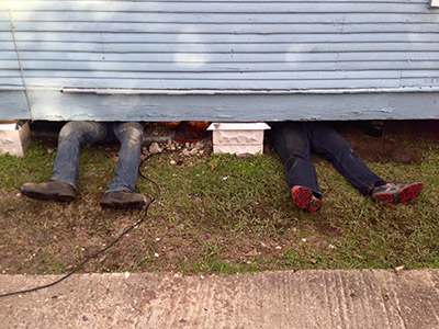 Photo of attorney's legs sticking out from under house during a home repair